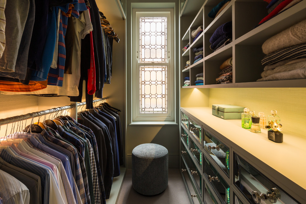Photo of a small traditional gender-neutral walk-in wardrobe in London with raised-panel cabinets, carpet and beige floor.