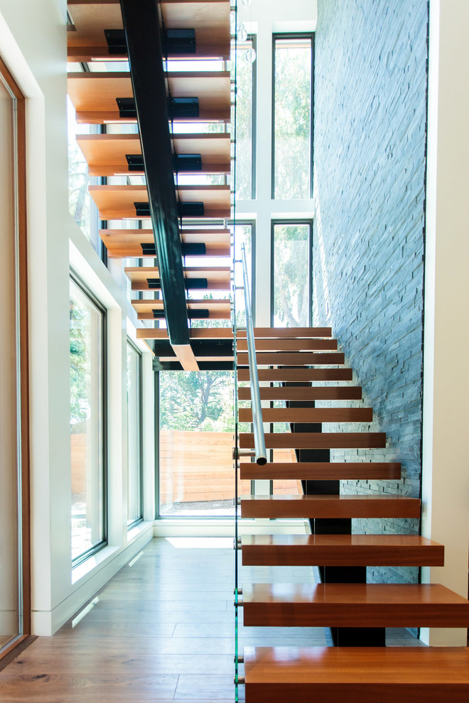 Large industrial wood u-shaped staircase in San Francisco with open risers and glass railing.