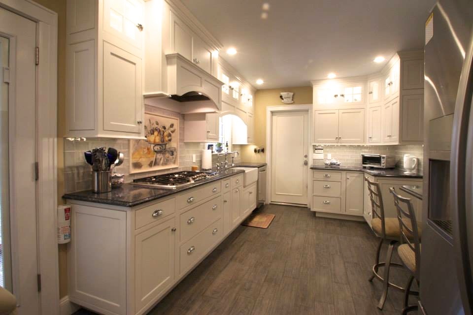 Photo of a small traditional galley separate kitchen in New York with a farmhouse sink, beaded inset cabinets, white cabinets, quartz benchtops, blue splashback, porcelain splashback, stainless steel appliances, porcelain floors and no island.