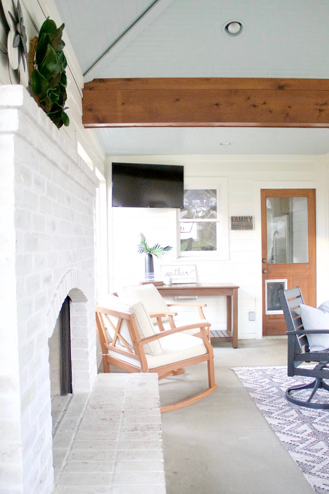 This is an example of a mid-sized transitional sunroom with concrete floors, a standard fireplace, a brick fireplace surround, a standard ceiling and grey floor.