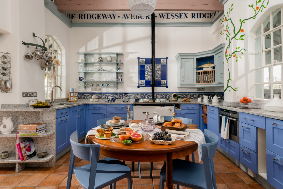 Photo of a nautical u-shaped kitchen/diner in Devon with a submerged sink, shaker cabinets, blue cabinets, blue splashback, white appliances, no island, brown floors and grey worktops.