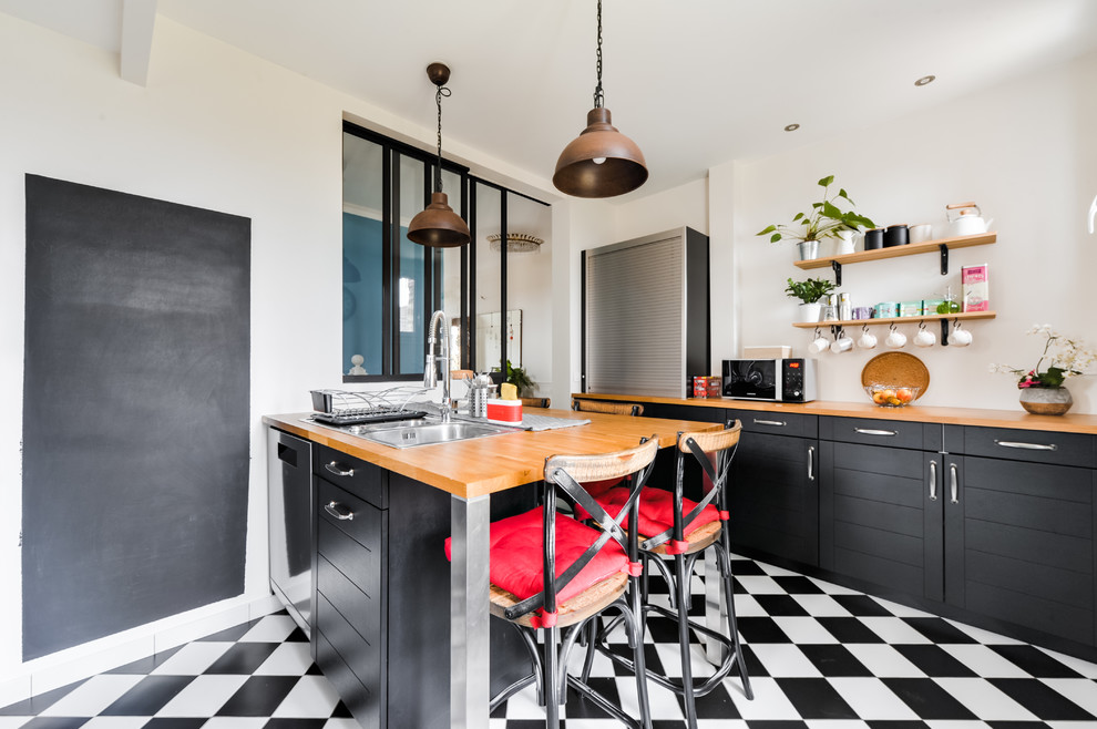 Design ideas for a mid-sized industrial galley separate kitchen in Paris with a double-bowl sink, black cabinets, wood benchtops, white splashback, a peninsula, shaker cabinets, subway tile splashback, stainless steel appliances, ceramic floors, black floor and brown benchtop.