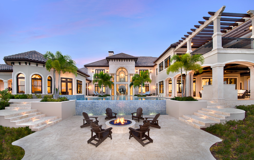 Inspiration for an expansive mediterranean backyard patio in Miami with natural stone pavers, a fire feature and no cover.
