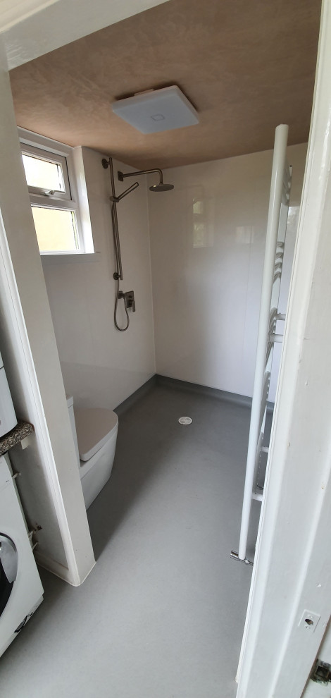 Mid-sized modern 3/4 wet room bathroom in Sussex with a two-piece toilet, white walls, a drop-in sink, grey floor, an enclosed toilet, a single vanity and panelled walls.