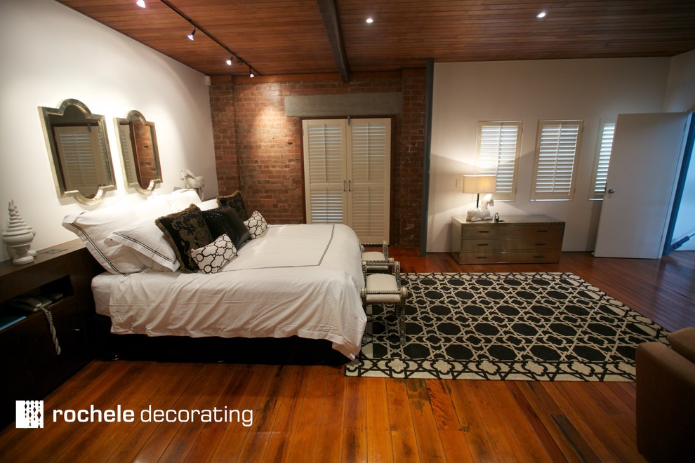 This is an example of a mid-sized industrial master bedroom in Brisbane with white walls and dark hardwood floors.