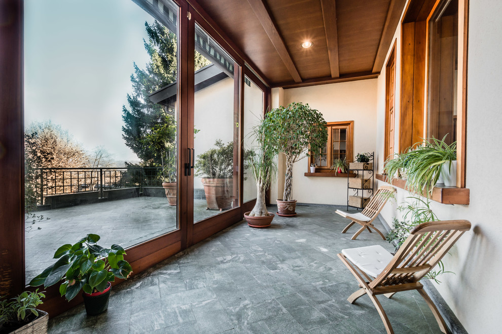 This is an example of a mid-sized country sunroom in Milan with limestone floors, a standard ceiling and grey floor.