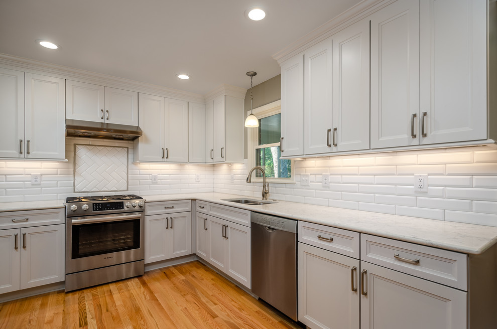 Small transitional l-shaped medium tone wood floor and brown floor eat-in kitchen photo with a double-bowl sink, shaker cabinets, gray cabinets, quartz countertops, white backsplash, subway tile backsplash, stainless steel appliances, no island and white countertops