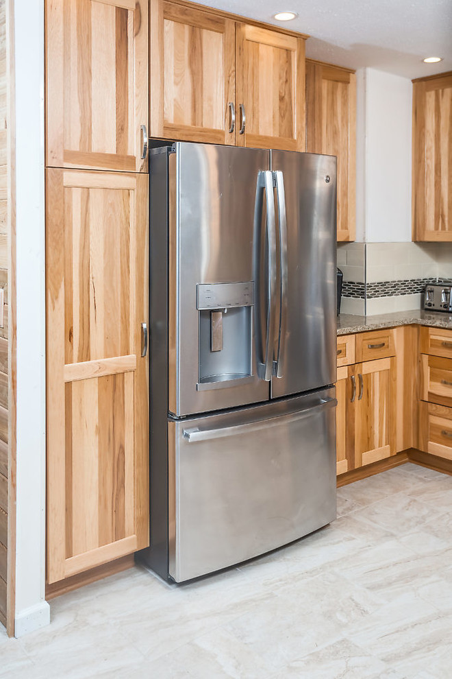 Example of a mid-sized transitional u-shaped enclosed kitchen design with an undermount sink, shaker cabinets, light wood cabinets, quartz countertops, white backsplash, subway tile backsplash, stainless steel appliances and no island