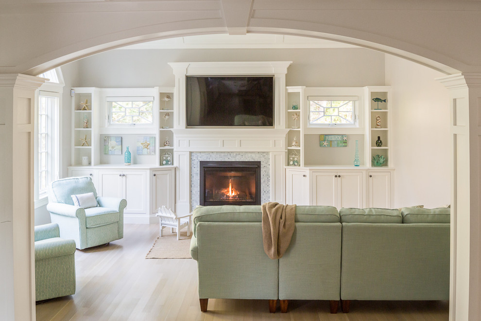 Inspiration for a large arts and crafts enclosed living room in Portland Maine with white walls, light hardwood floors, a standard fireplace, a plaster fireplace surround and a wall-mounted tv.