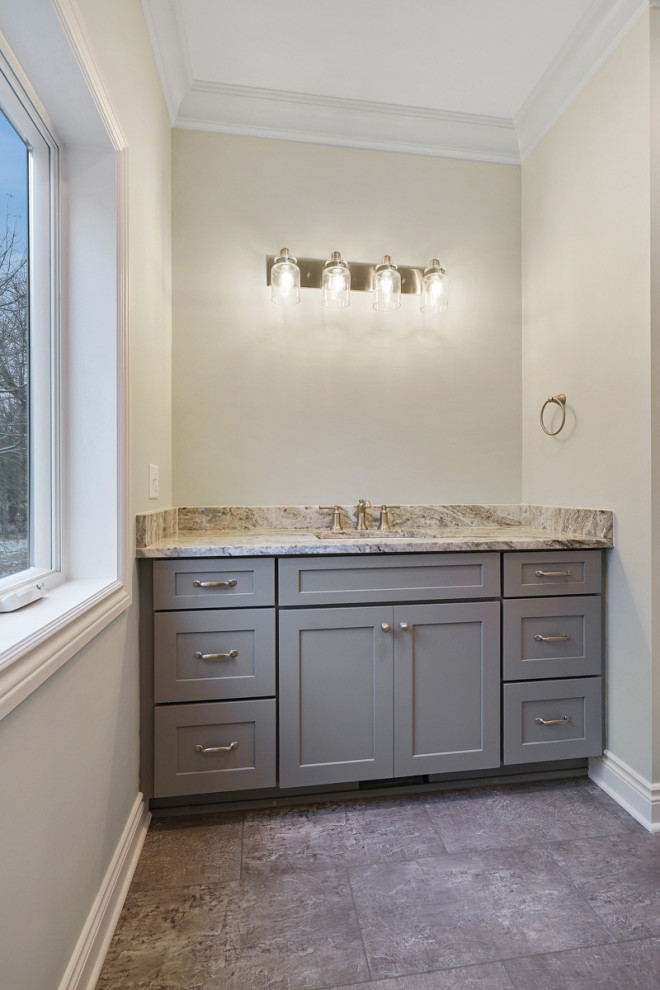 Design ideas for a mid-sized traditional 3/4 bathroom in Detroit with shaker cabinets, grey cabinets, an alcove tub, a shower/bathtub combo, an undermount sink, granite benchtops, a shower curtain, multi-coloured benchtops, a single vanity, a built-in vanity, beige walls, laminate floors and grey floor.