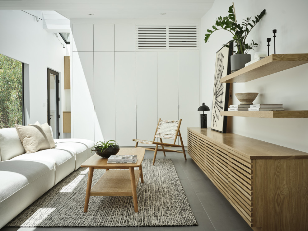 Immagine di un grande soggiorno minimalista aperto con pareti bianche, pavimento in gres porcellanato, TV a parete, pavimento grigio e soffitto a volta
