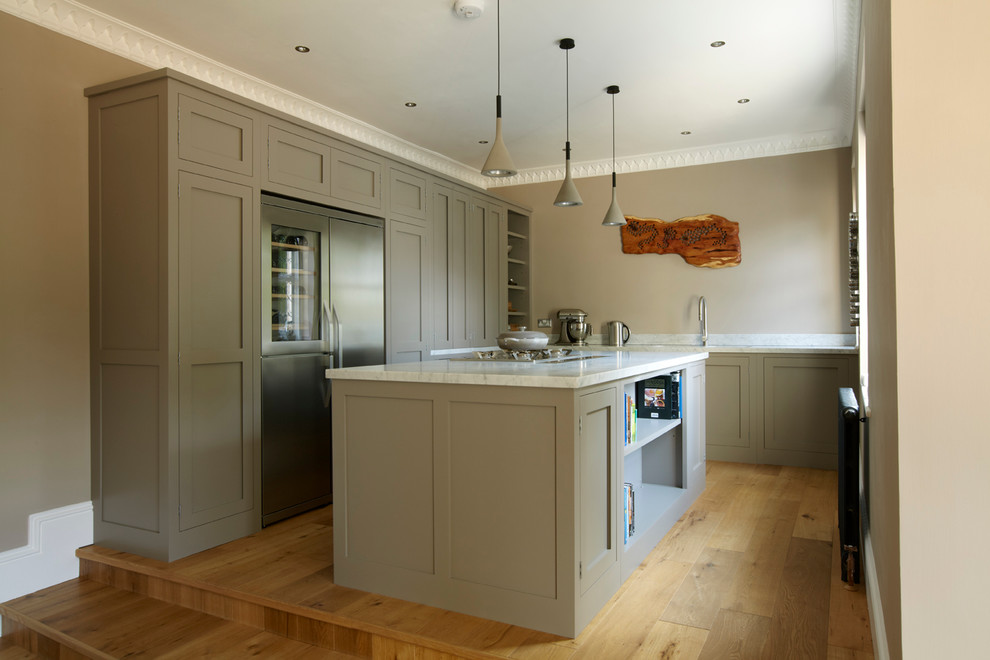Photo of a mid-sized contemporary l-shaped open plan kitchen in London with shaker cabinets, marble benchtops, stainless steel appliances, medium hardwood floors and with island.