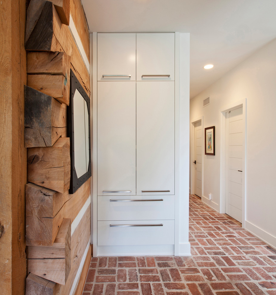 This is an example of a mid-sized contemporary hallway in Indianapolis with white walls and brick floors.