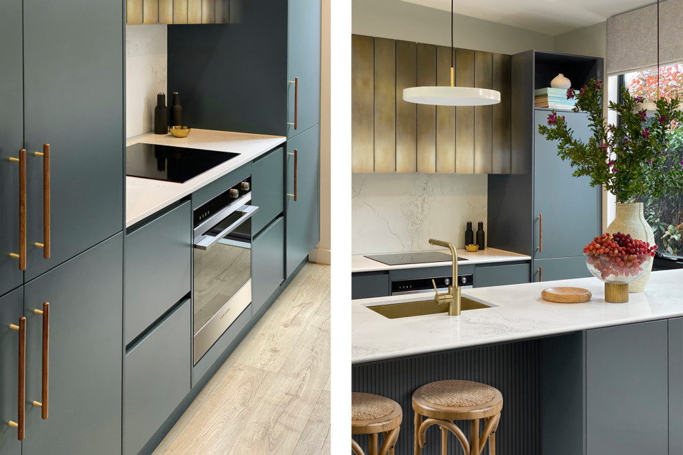 This is an example of a mid-sized modern galley kitchen pantry in Melbourne with an undermount sink, recessed-panel cabinets, blue cabinets, marble benchtops, white splashback, marble splashback, stainless steel appliances, light hardwood floors, with island, brown floor, white benchtop and recessed.
