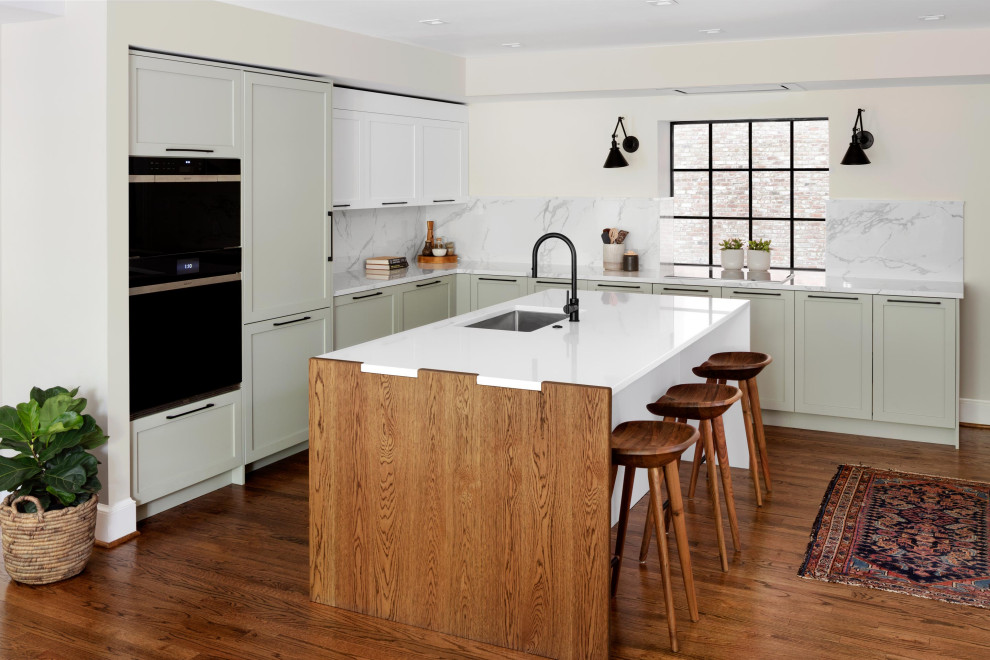 Large trendy l-shaped medium tone wood floor and brown floor open concept kitchen photo in DC Metro with an undermount sink, recessed-panel cabinets, gray cabinets, quartz countertops, white backsplash, porcelain backsplash, black appliances, an island and white countertops