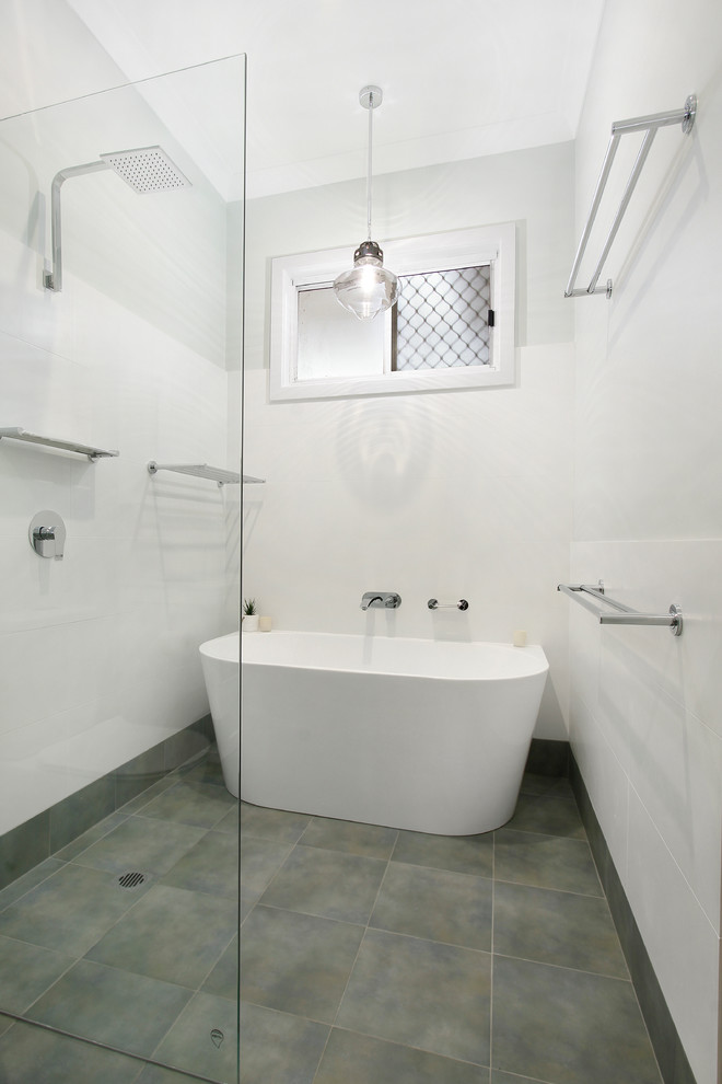 Inspiration for a large transitional master bathroom in Wollongong with louvered cabinets, white cabinets, a freestanding tub, a curbless shower, a one-piece toilet, white tile, white walls, ceramic floors, an integrated sink, grey floor, an open shower and white benchtops.