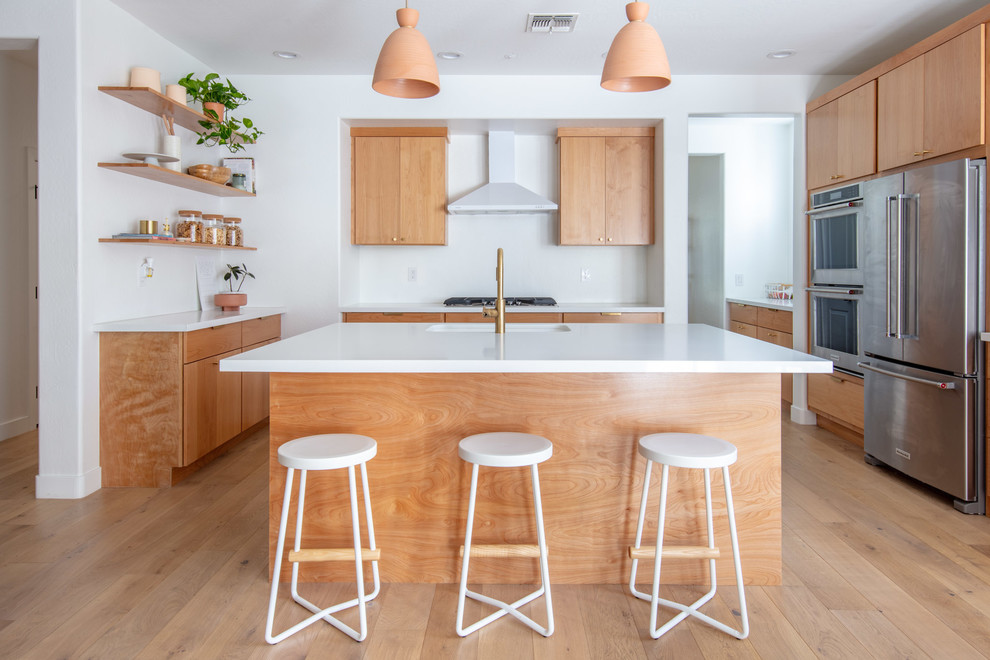 Design ideas for a mid-sized midcentury kitchen in Phoenix with flat-panel cabinets, light wood cabinets, quartz benchtops, white splashback, stainless steel appliances, light hardwood floors, with island, white benchtop, a single-bowl sink and beige floor.