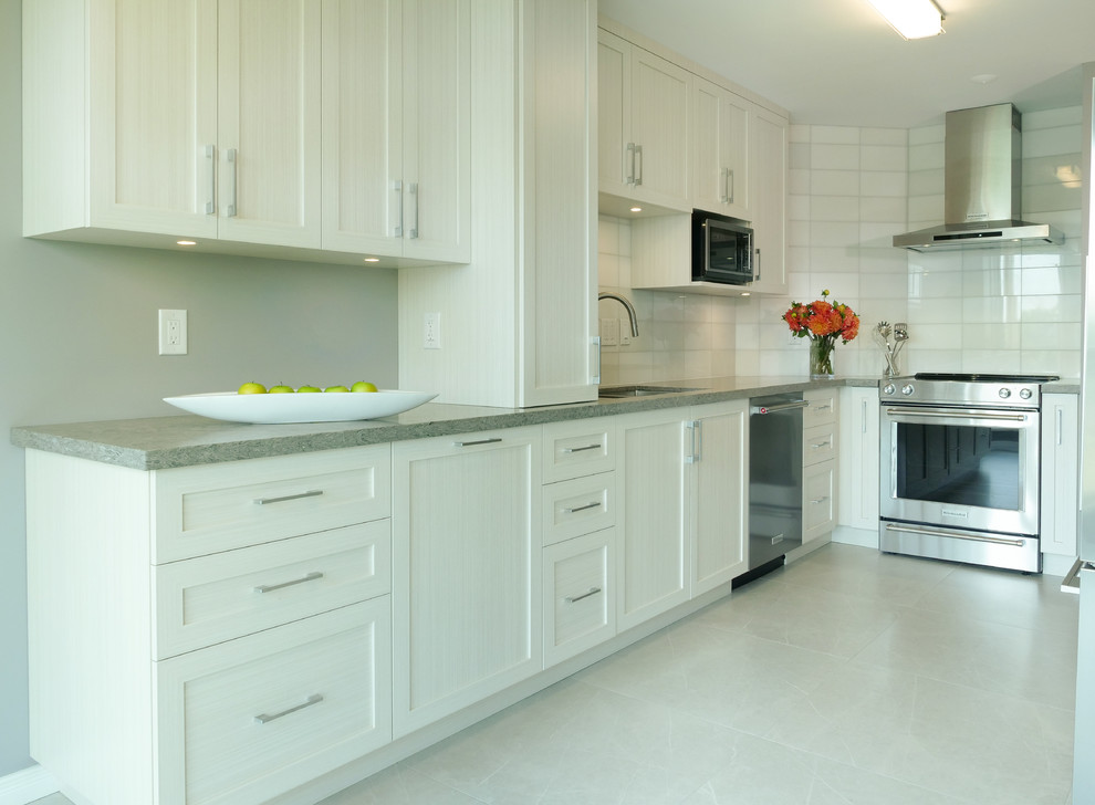 This is an example of a small transitional galley separate kitchen in Toronto with shaker cabinets, white cabinets, quartzite benchtops, red splashback, stainless steel appliances, porcelain floors, no island and grey floor.