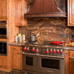 Inspiration for a large rustic u-shaped slate floor eat-in kitchen remodel with an undermount sink, raised-panel cabinets, distressed cabinets, granite countertops, multicolored backsplash, stone slab backsplash, stainless steel appliances and a peninsula