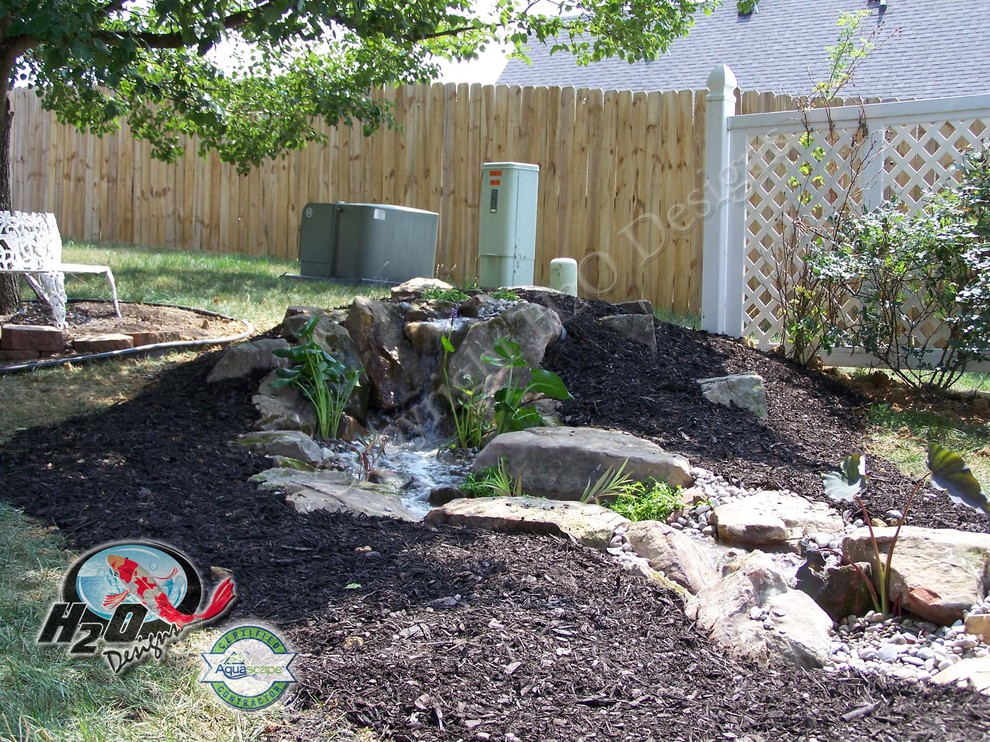 Large eclectic backyard partial sun garden in Other with a water feature and mulch.