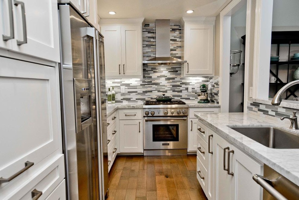 Design ideas for a mid-sized transitional galley separate kitchen in San Francisco with an undermount sink, shaker cabinets, white cabinets, marble benchtops, grey splashback, matchstick tile splashback, stainless steel appliances, light hardwood floors and a peninsula.