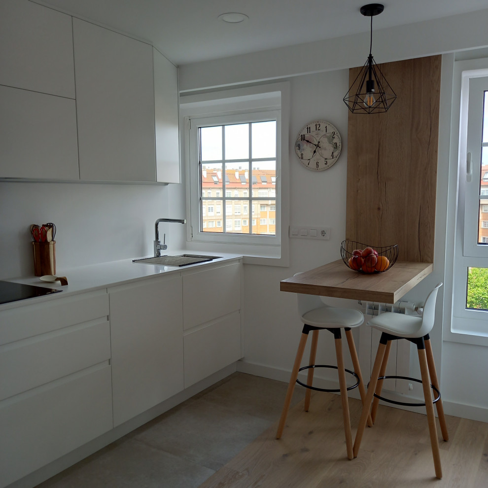 Skandinavisk inredning av ett mellanstort, avskilt vit vitt l-kök, med en undermonterad diskho, släta luckor, vita skåp, vitt stänkskydd, vita vitvaror och mellanmörkt trägolv