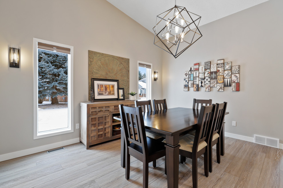 Photo of a medium sized contemporary kitchen/dining room in Calgary with beige walls, light hardwood flooring, a corner fireplace, a stone fireplace surround and beige floors.