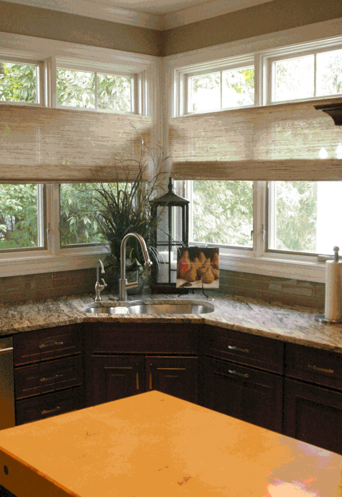 Mid-sized transitional l-shaped kitchen photo with a double-bowl sink, raised-panel cabinets, dark wood cabinets, granite countertops, gray backsplash, glass tile backsplash, stainless steel appliances and an island