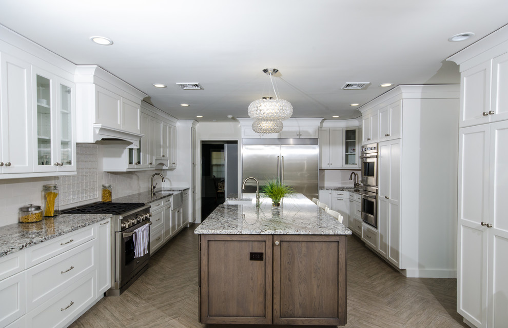 Design ideas for a large transitional u-shaped eat-in kitchen in New York with a farmhouse sink, shaker cabinets, white cabinets, granite benchtops, white splashback, stainless steel appliances, porcelain floors, with island, ceramic splashback and beige floor.