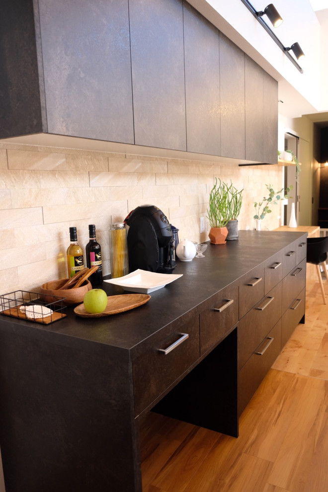 Offene, Zweizeilige Küche mit schwarzen Elektrogeräten, hellem Holzboden, Tapetendecke und schwarzen Schränken in Sonstige
