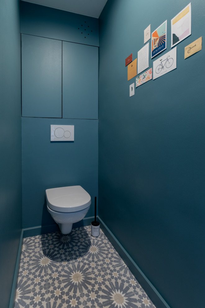 На фото: туалет среднего размера в классическом стиле с синими фасадами, инсталляцией, полом из цементной плитки, разноцветным полом и встроенной тумбой с