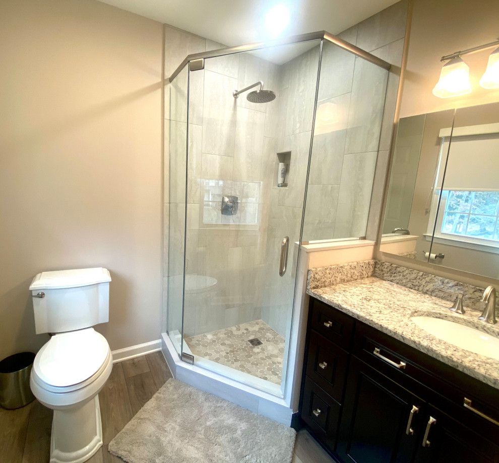 Example of a small transitional master beige tile and porcelain tile vinyl floor, brown floor and single-sink corner shower design in Philadelphia with raised-panel cabinets, brown cabinets, a one-piece toilet, beige walls, an undermount sink, granite countertops, a hinged shower door, beige countertops, a niche and a built-in vanity