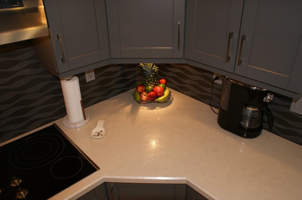 Example of a mid-sized transitional light wood floor and brown floor kitchen design in Orange County with shaker cabinets, gray cabinets, an island, brown backsplash and black appliances