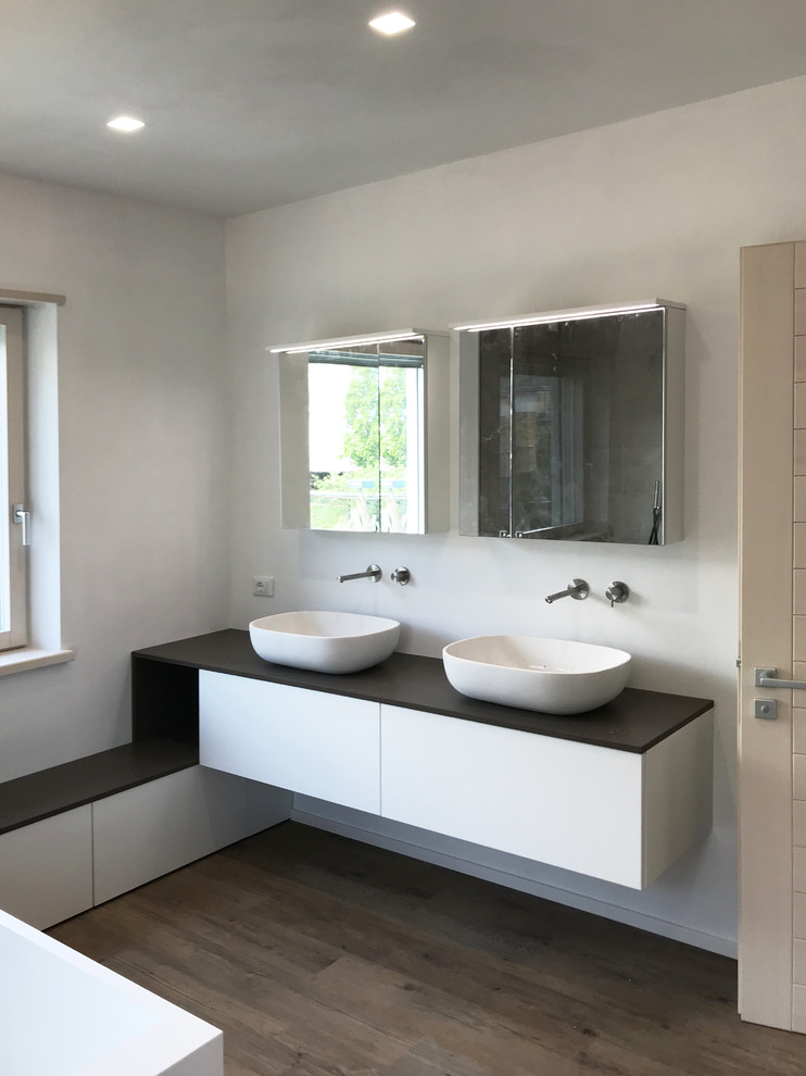 Inspiration for a large contemporary master bathroom in Other with flat-panel cabinets, white cabinets, a freestanding tub, an open shower, porcelain tile, vinyl floors, a vessel sink, engineered quartz benchtops, brown floor, an open shower and brown benchtops.