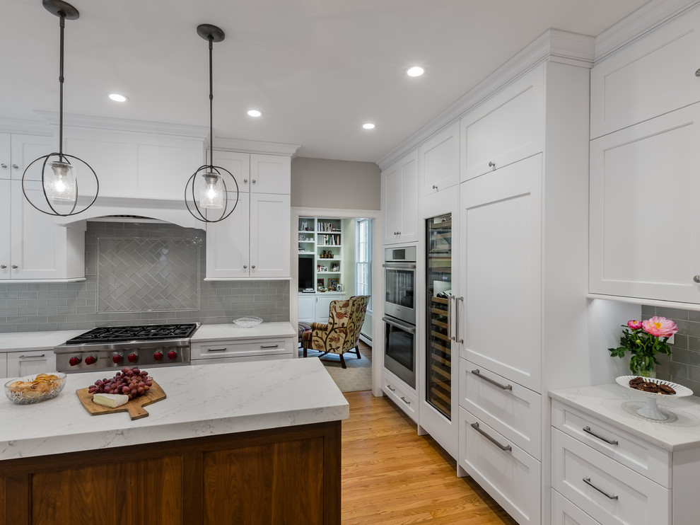 Inspiration for a transitional u-shaped eat-in kitchen remodel in Providence with an undermount sink, white cabinets, quartzite countertops, glass tile backsplash, stainless steel appliances and an island