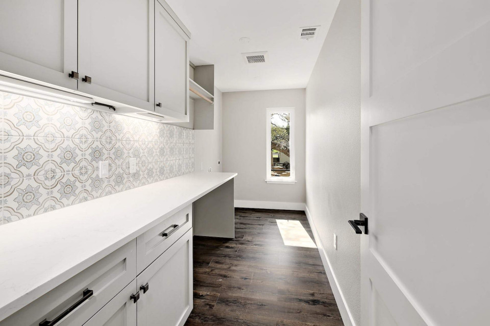 This is an example of a mid-sized transitional utility room in Austin with shaker cabinets, grey cabinets, quartz benchtops, ceramic splashback, dark hardwood floors, a side-by-side washer and dryer, brown floor and white benchtop.