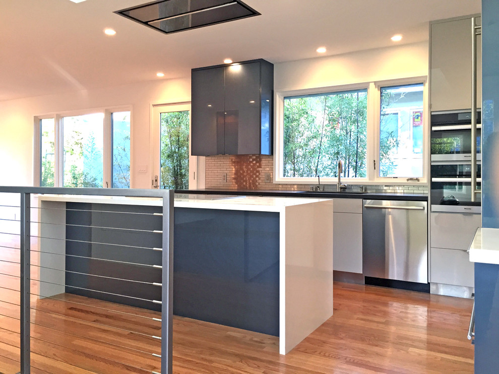 Example of a mid-sized minimalist u-shaped light wood floor eat-in kitchen design in San Francisco with an undermount sink, flat-panel cabinets, blue cabinets, quartz countertops, metallic backsplash, metal backsplash, stainless steel appliances and an island