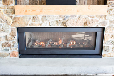 Example of a mid-sized mountain style concrete floor home design design with a stone fireplace and a wall-mounted tv