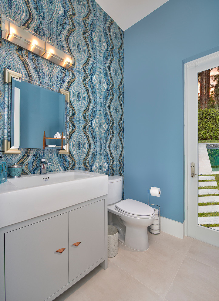 Design ideas for a contemporary powder room in Miami with beaded inset cabinets, grey cabinets, a two-piece toilet, blue walls, a vessel sink and beige floor.