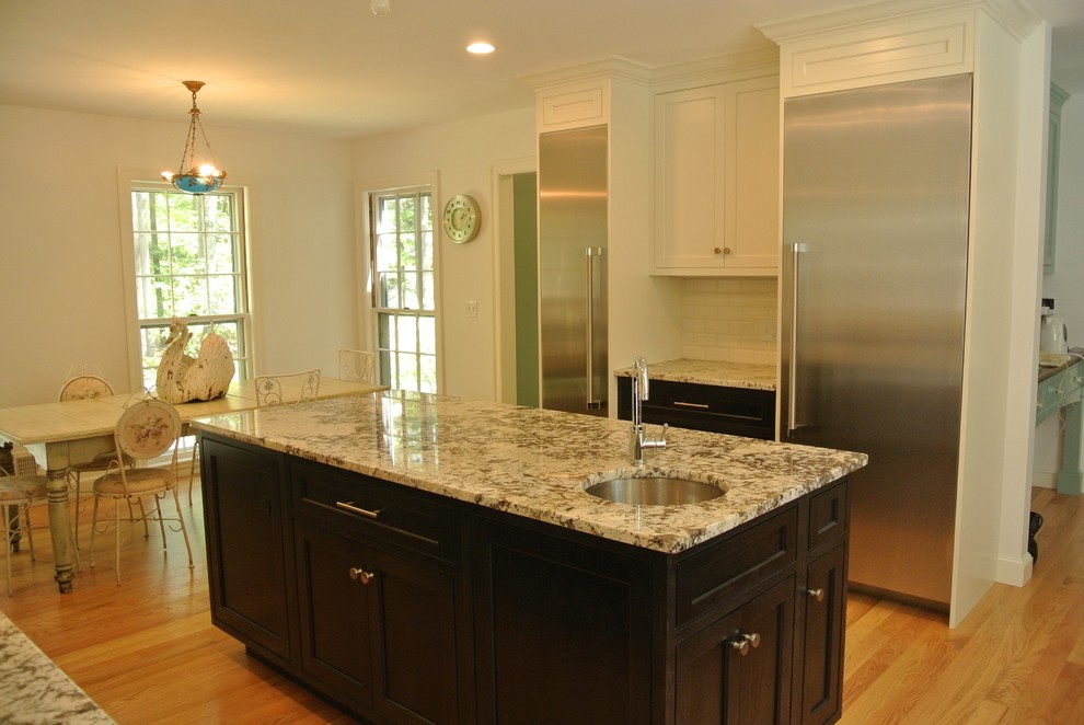 Example of a transitional light wood floor eat-in kitchen design in Boston with an undermount sink, shaker cabinets, granite countertops, white backsplash, subway tile backsplash, stainless steel appliances and an island