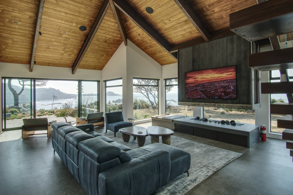Inspiration for a large modern open concept living room in San Francisco with grey walls, concrete floors, a hanging fireplace, a stone fireplace surround, a wall-mounted tv, grey floor, exposed beam and panelled walls.