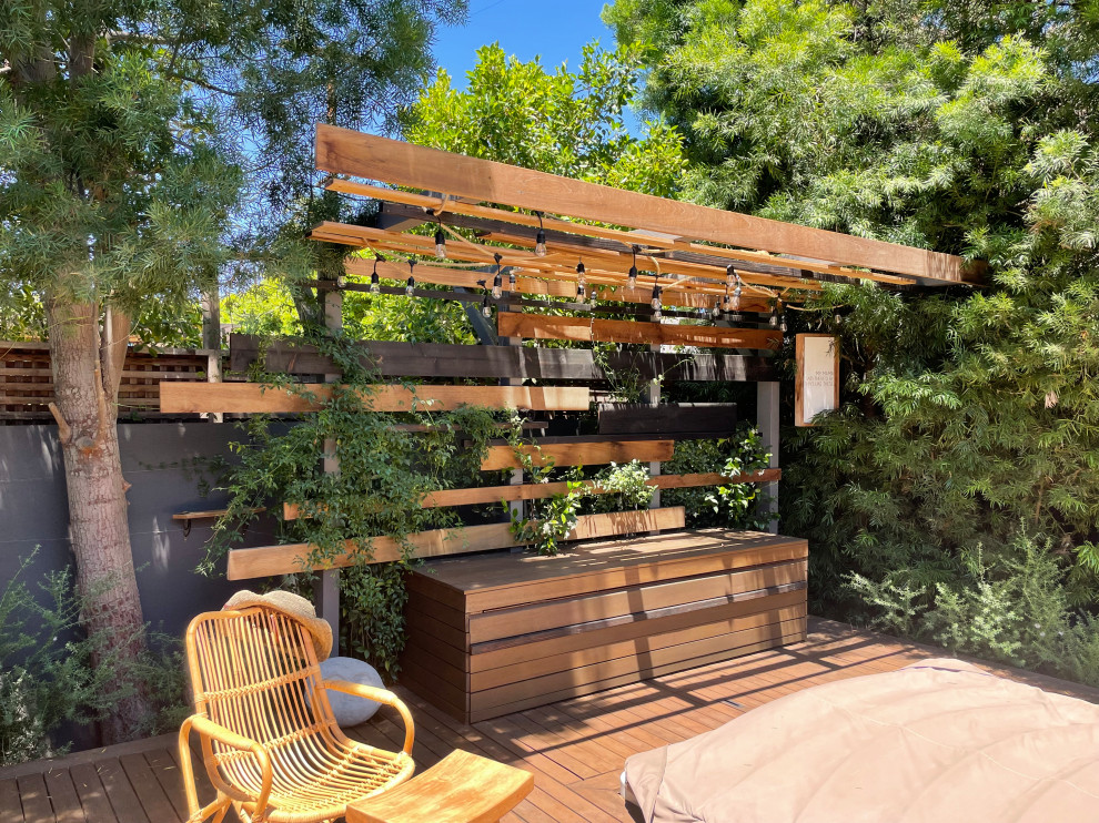 Inspiration for a mid-sized eclectic backyard full sun xeriscape for spring in Los Angeles with with privacy feature, decking and a wood fence.