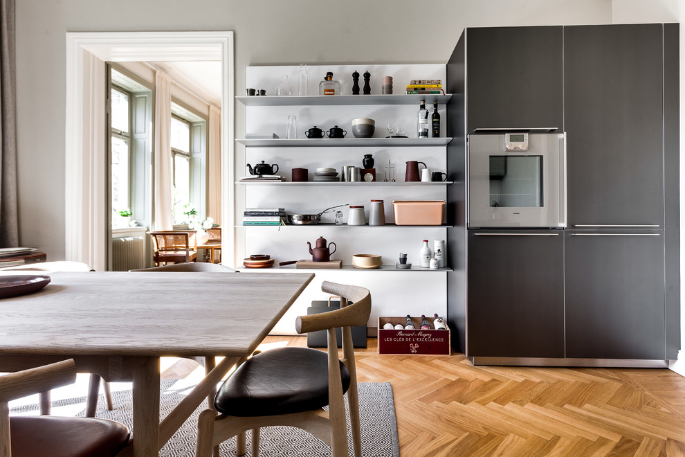 This is an example of a mid-sized scandinavian kitchen in Stockholm with open cabinets, black appliances, medium hardwood floors and no island.