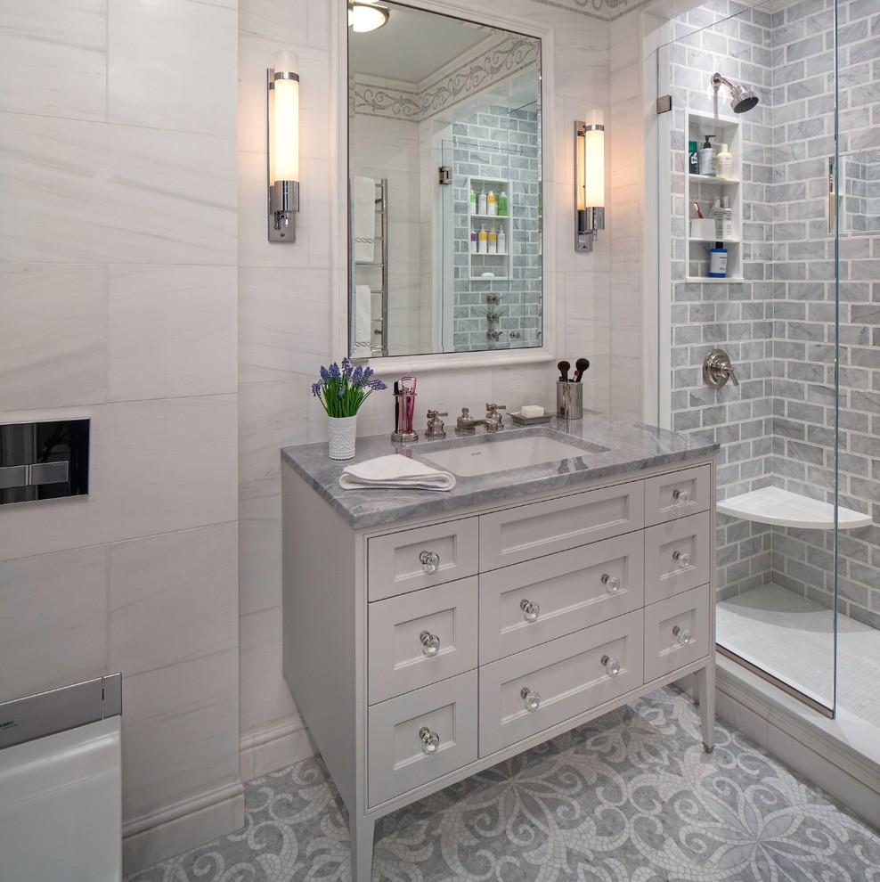 Photo of a mid-sized transitional master bathroom in New York with an undermount sink, shaker cabinets, grey cabinets, marble benchtops, a double shower, a wall-mount toilet, gray tile, stone tile, grey walls and mosaic tile floors.