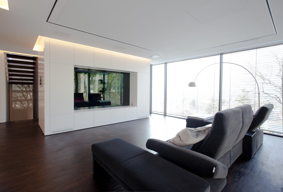 Inspiration for a large modern open concept home theatre in Frankfurt with white walls, dark hardwood floors and a built-in media wall.