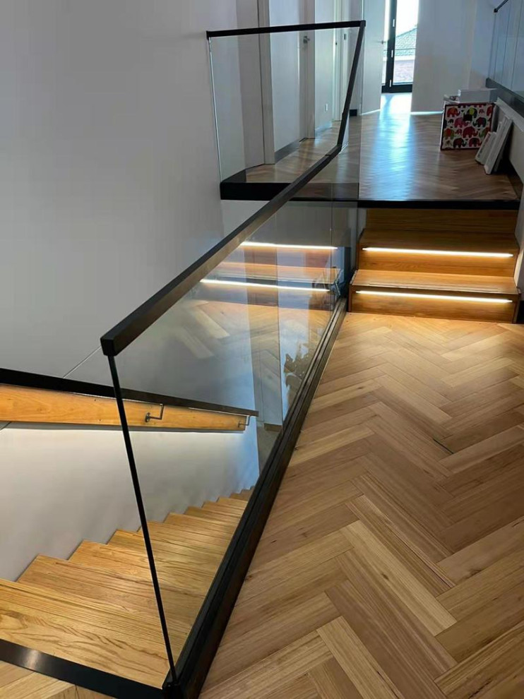 Mid-sized modern wood straight staircase in Melbourne with open risers, glass railing and wallpaper.