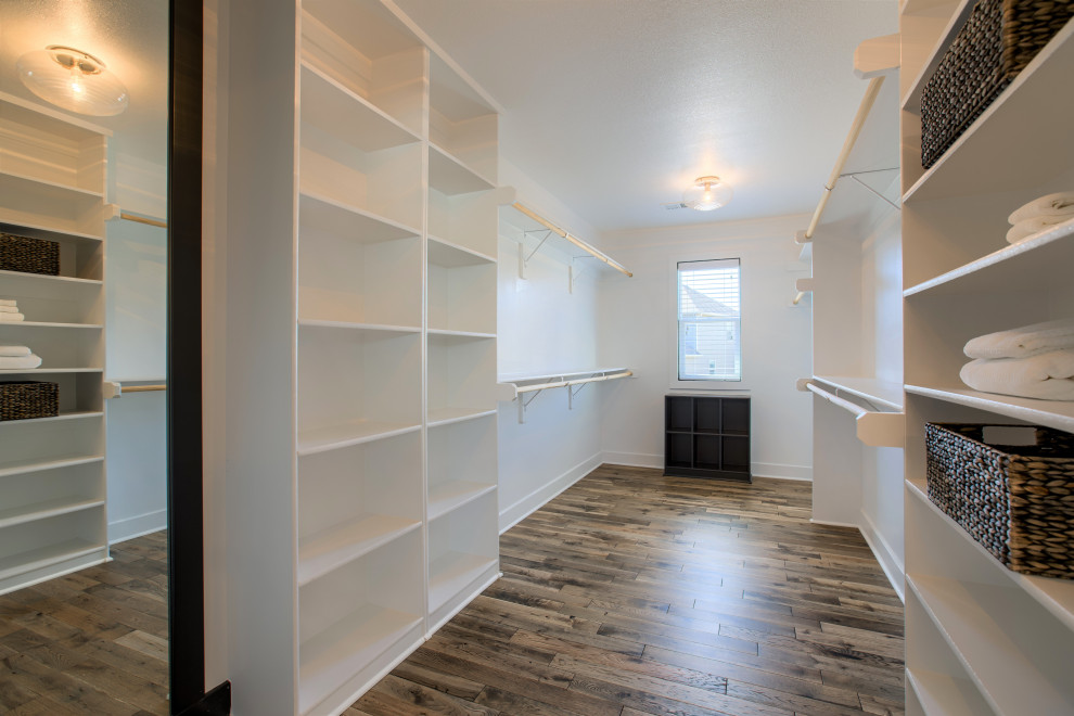 Photo of a large country gender-neutral walk-in wardrobe in Kansas City with shaker cabinets, white cabinets, painted wood floors and brown floor.