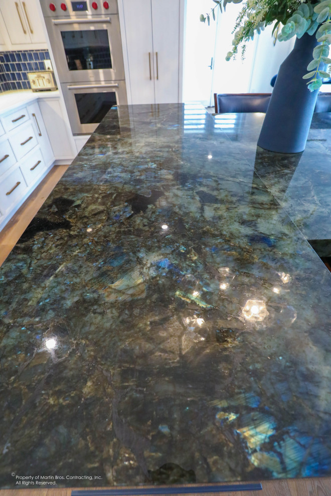 Open concept kitchen - large transitional u-shaped medium tone wood floor open concept kitchen idea with a single-bowl sink, flat-panel cabinets, white cabinets, quartz countertops, blue backsplash, glass tile backsplash, stainless steel appliances, an island and white countertops