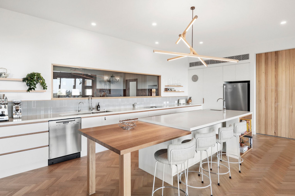 Design ideas for a contemporary separate kitchen in Geelong with a double-bowl sink, flat-panel cabinets, white cabinets, quartz benchtops, grey splashback, stainless steel appliances, medium hardwood floors, with island, brown floor and white benchtop.