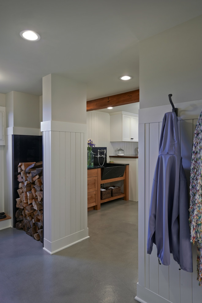Traditional galley utility room in Seattle with a farmhouse sink, shaker cabinets, white cabinets, soapstone benchtops, white walls, concrete floors and a side-by-side washer and dryer.